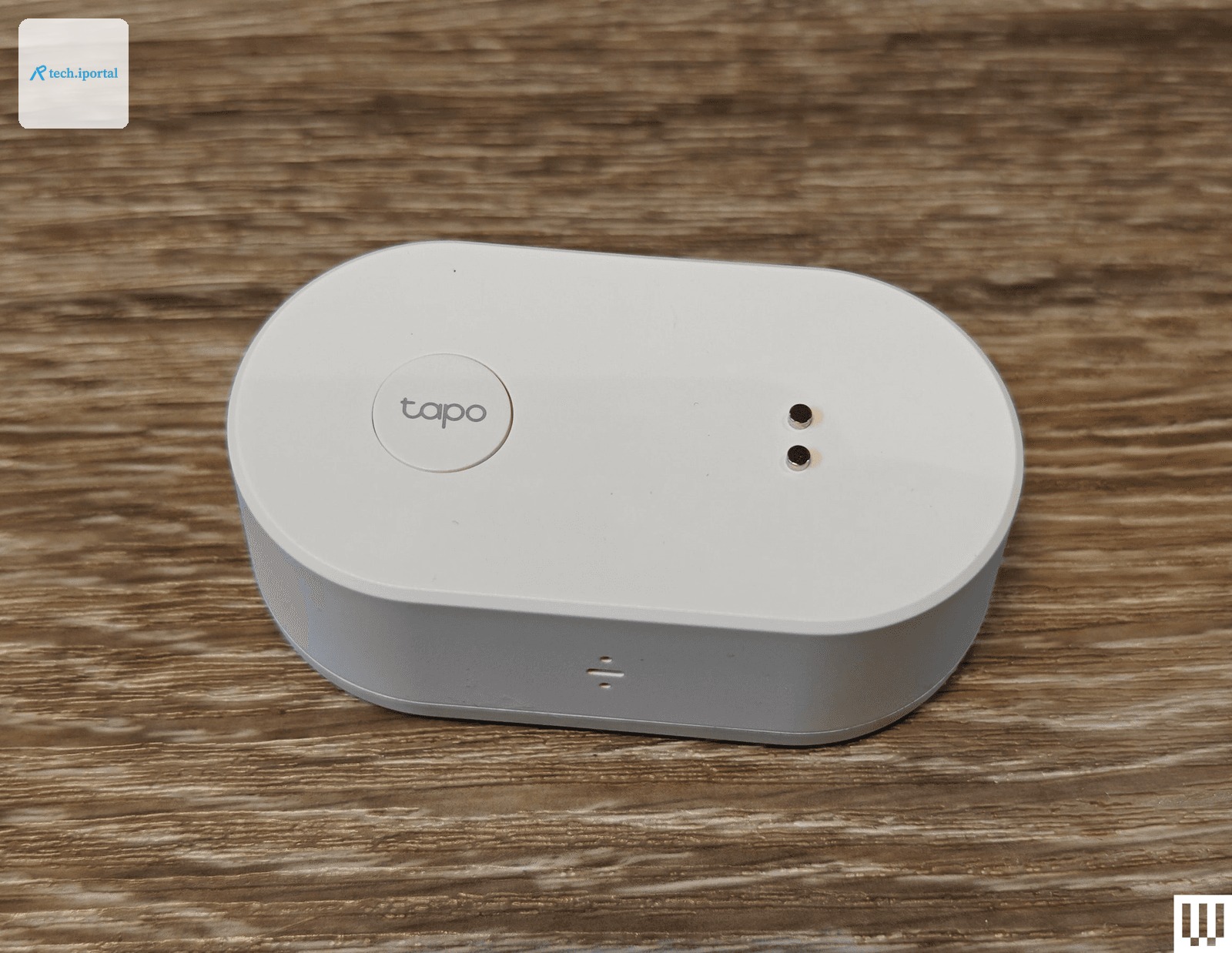 White oval shaped device sitting on wooden surface. Product is branded with the name Tapo.