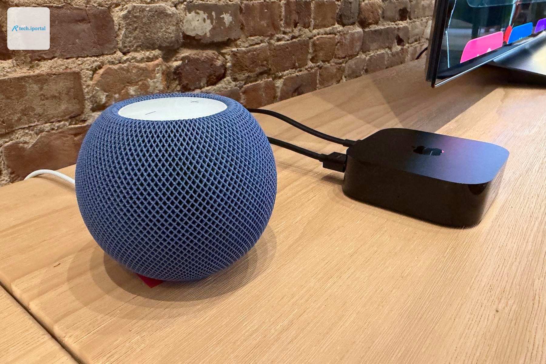 The Apple HomePod Mini 2 and 4th-generation Apple TV 4K on a tan wooden table at the Apple Welcome Home event.