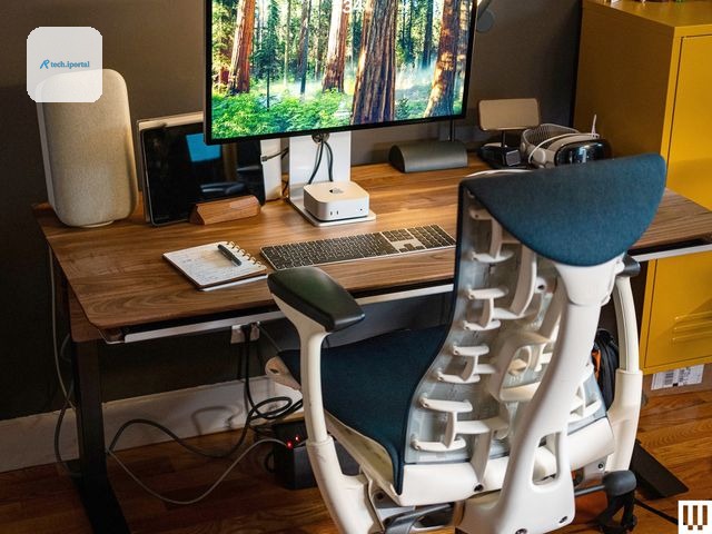 Grovemade Desk with brown top beside an ergonomic office chair and computer monitor keyboard and speakers on top