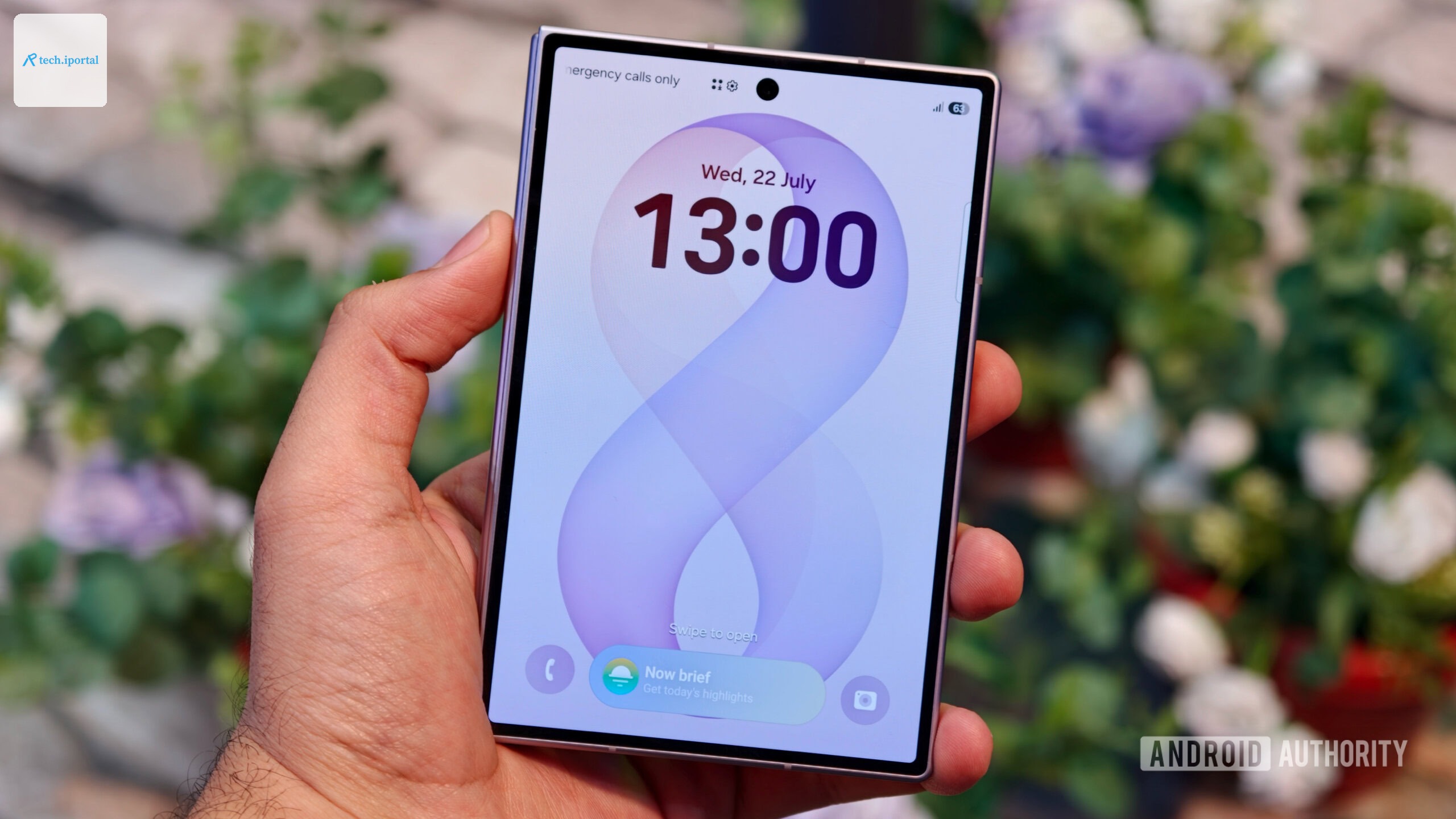 A hand holding the closed Samsung Galaxy Z Fold 8 showing its outer cover display with a digital clock and wallpaper