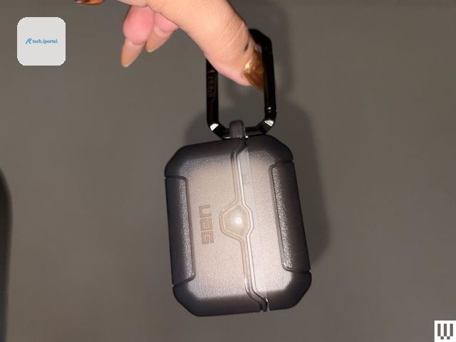 Hand pinching a small rectangular case by the keychain attached