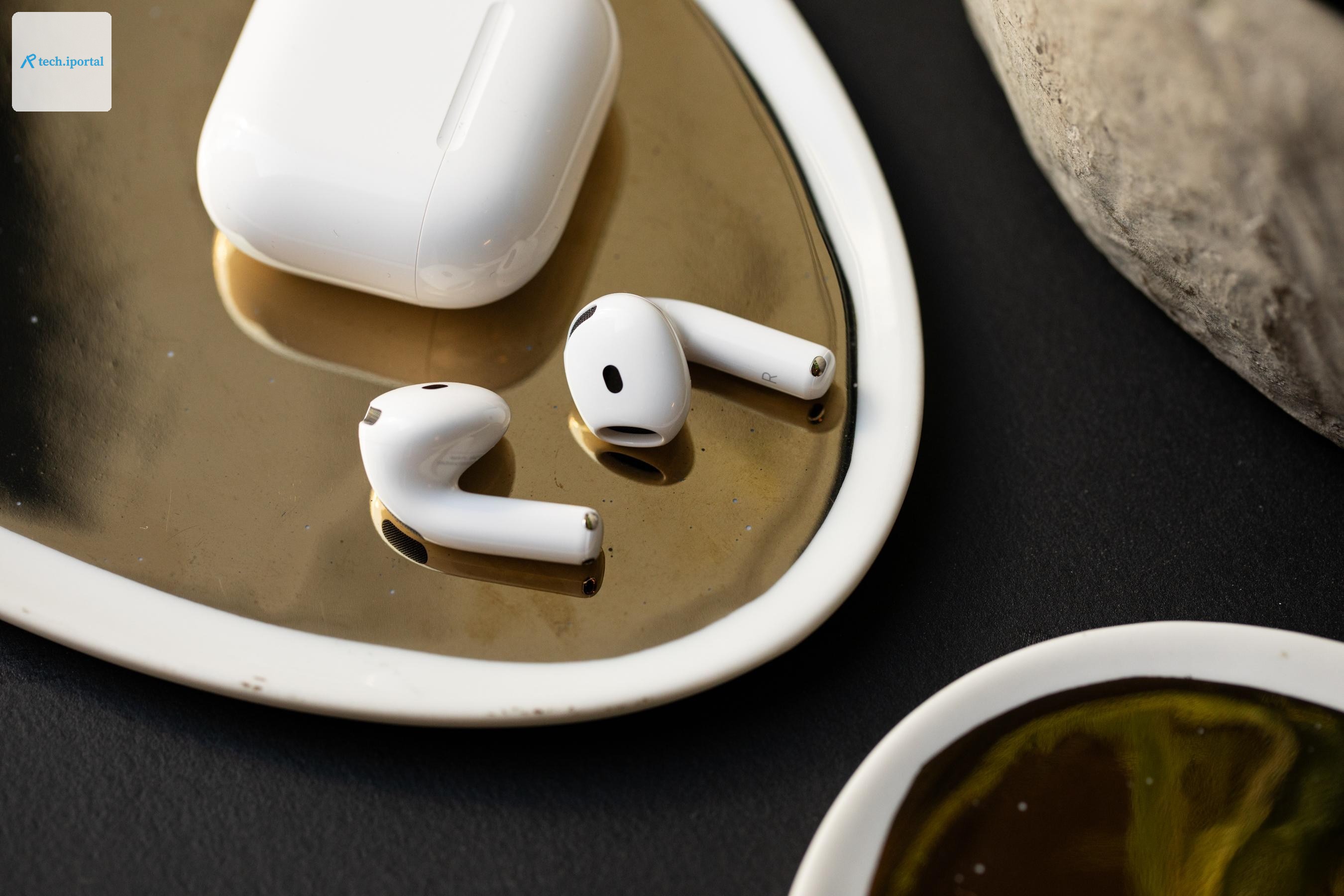 The AirPods 5 next to their wireless charging case.