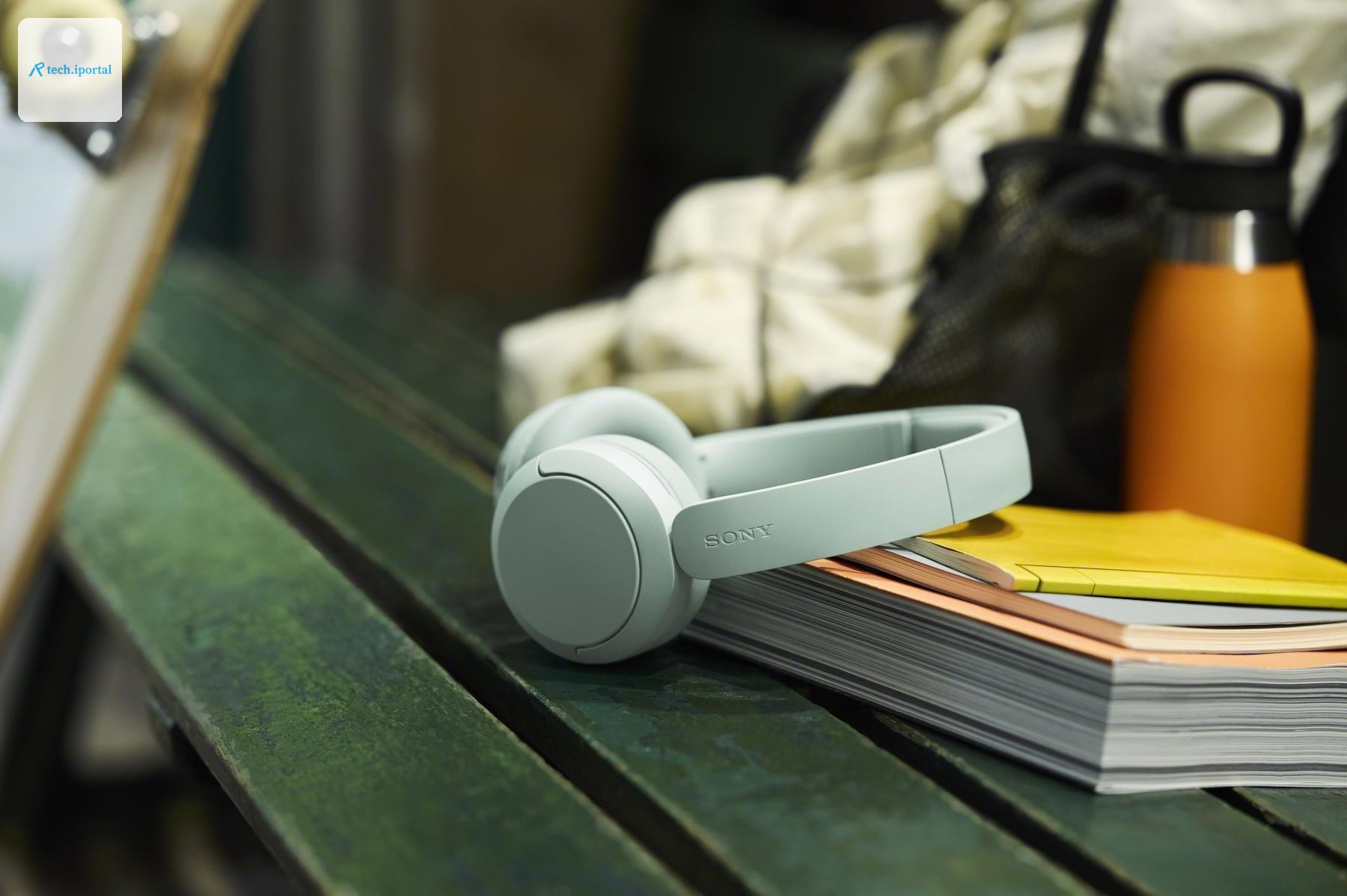 Green Sony WH-CH530 headphones resting against some books on a bench.