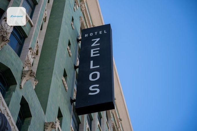 Vertical sign for Hotel Zelos on green tiled historic facade under clear blue sky, San Francisco, California, August 19, 2025.