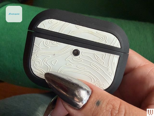 Person's hand pinching a small white case with rounded edges and black trim
