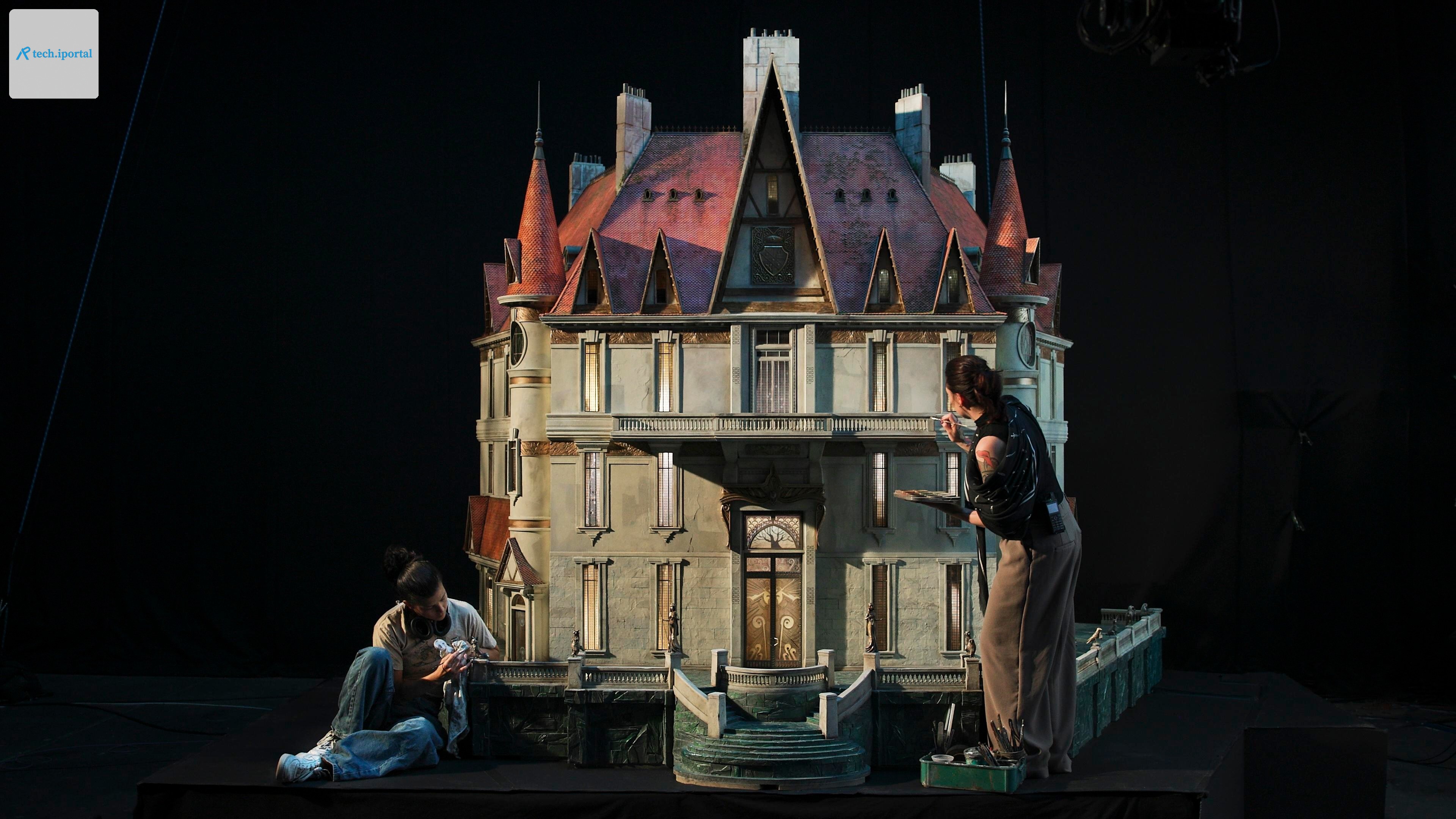 Two people work on a model of a grand-looking house that looks about 10 feet tall and will be used for an animated film.