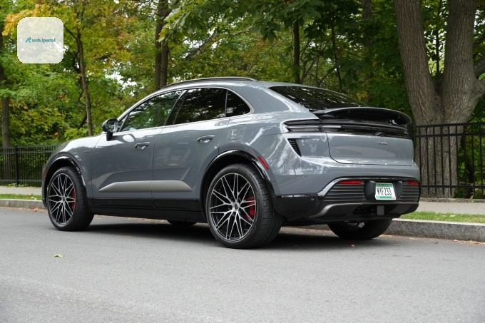 An electric Porsche Macan sits parked with its spoiler deployed.