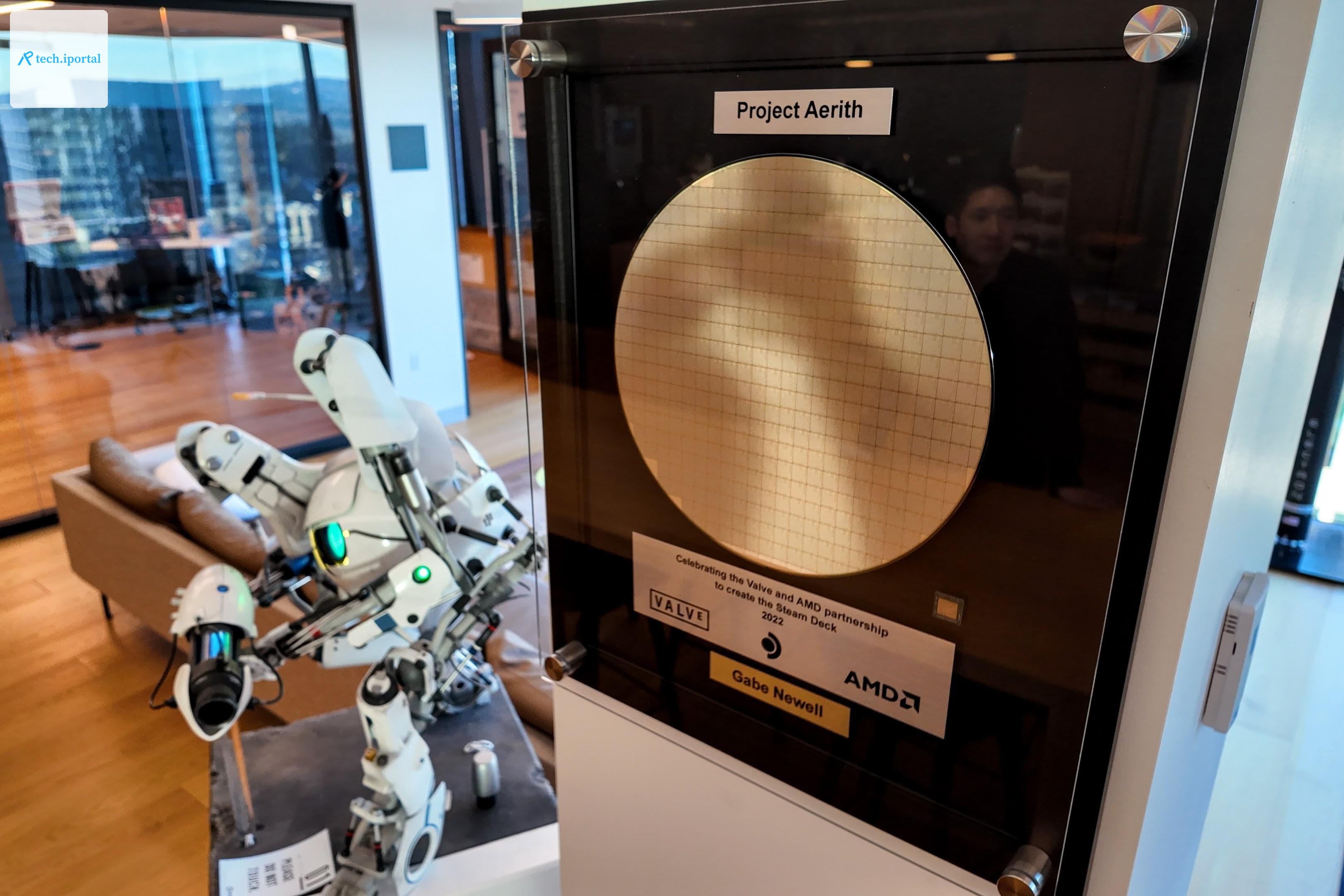 A Project Aerith wafer on Valve’s HQ walls, in a display case. It’s a gold shiny disc with chips on it, with plaques for AMD and Gabe Newell and one that reads Project Aerith