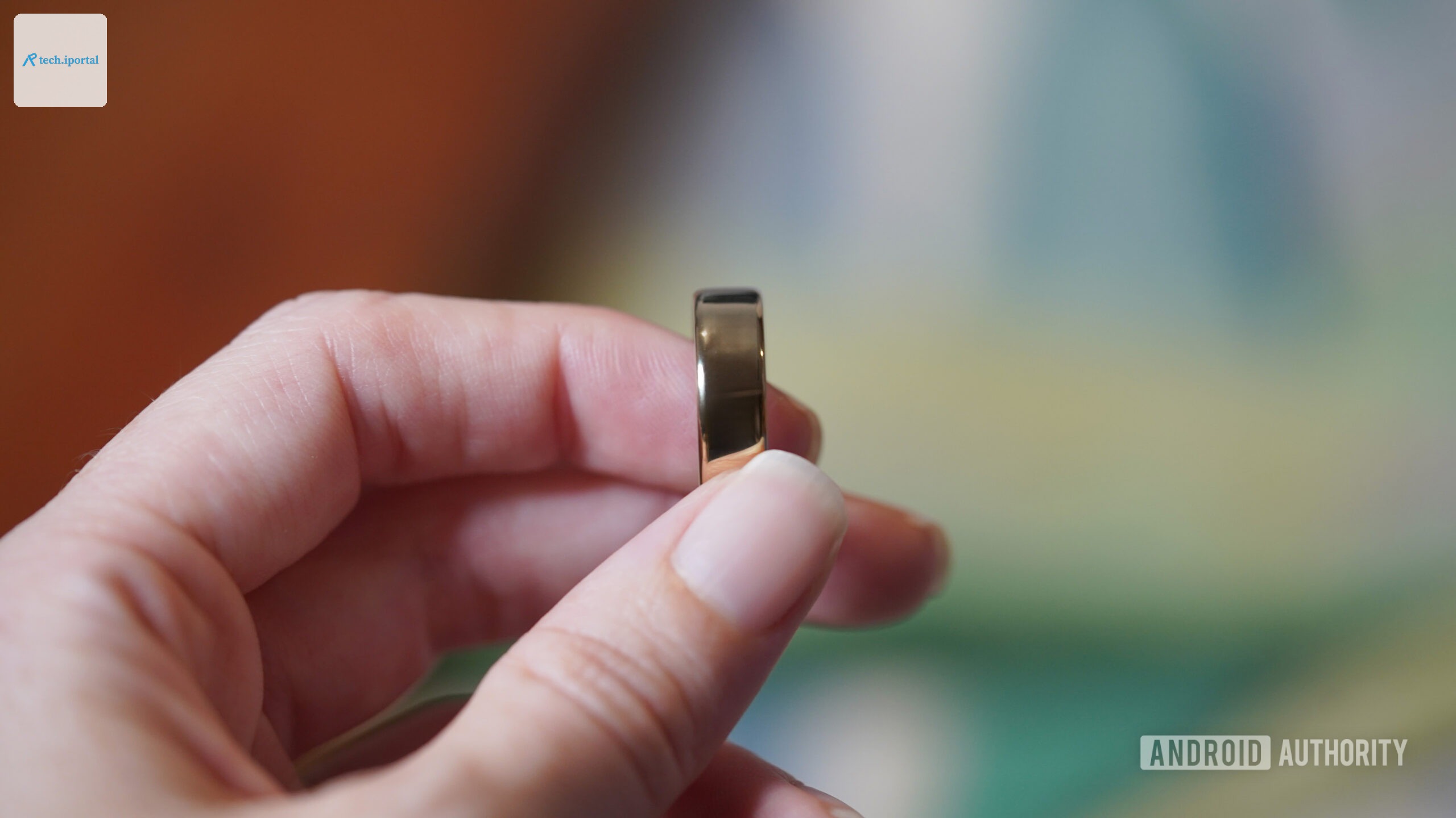 A user holds a Gold Oura Ring 5 between their fingers.