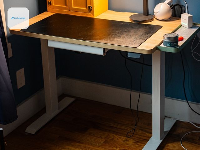 Branch Duo Standing Desk with light brown top and white legs that has a small cabinet black cutting mat and lamp on the top