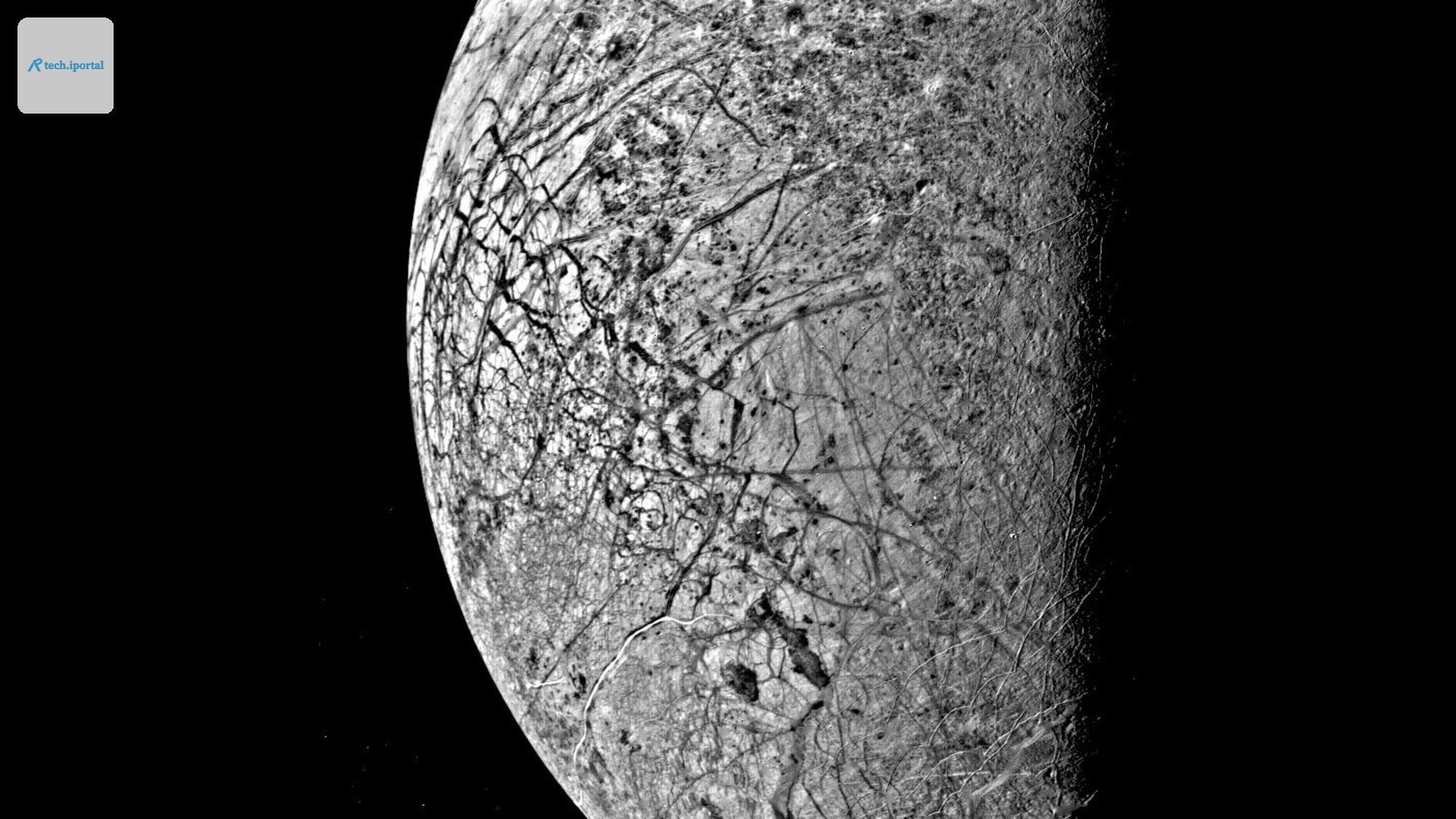 darkness obscures half of a grey orb crisscrossed with deep lines and cracks